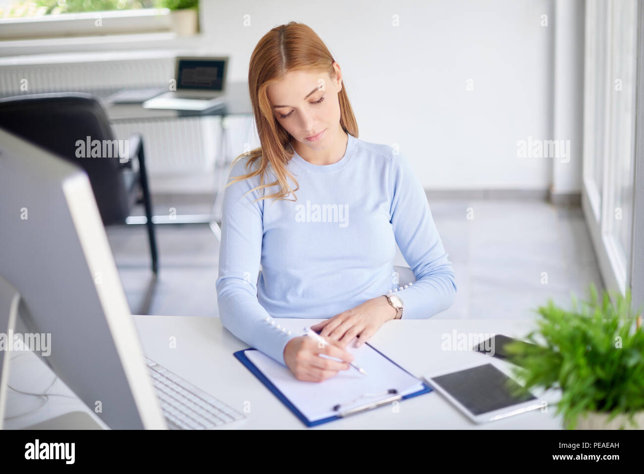 Alta angolazione del giovane imprenditrice seduta in ufficio e facendo alcuni documenti. Foto Stock