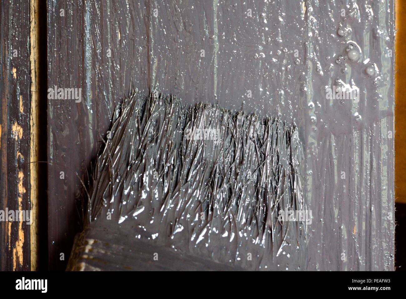 Il pennello è tinto con una vernice di colore grigio. La superficie di legno è coperto con un colore scuro vernice. Foto Stock