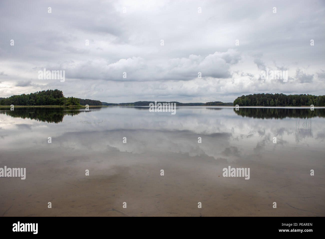 Bella riflessione di una foresta e cielo molto nuvoloso in acqua calma Foto Stock