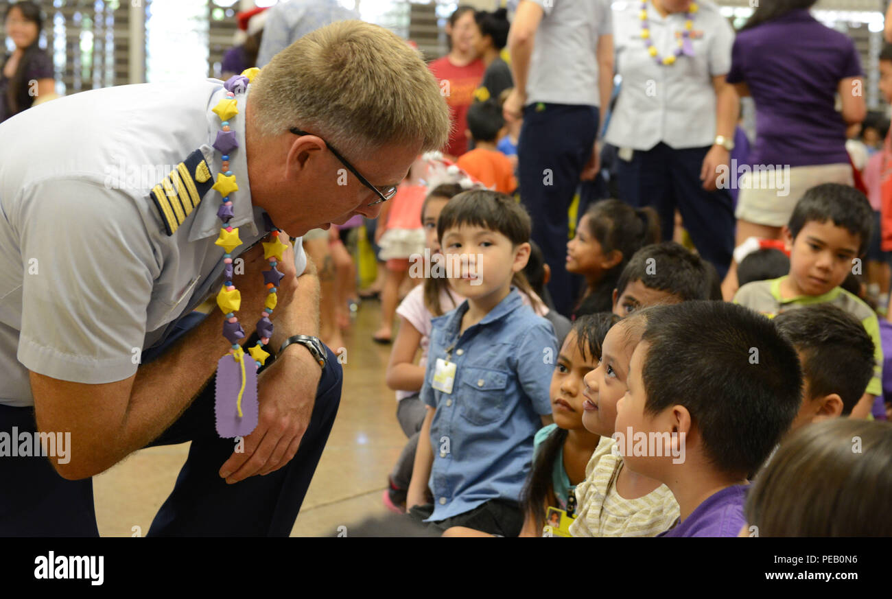 Il cap. James Jenkins, Coast Guard quattordicesimo distretto capo del personale, parla con i bambini dopo una vacanza musicale cerimonia in Kuhio Scuola Elementare di Honolulu, il 4 dicembre, 2015. I membri dell'equipaggio da Oahu-basato Coast Guard unità consegnate i regali di Natale per 300 bambini presso un centro cittadino di Honolulu School che preleva da un area di diseredati dell isola di Oahu. (U.S. Coast Guard foto di Sottufficiali di 2a classe di Tara Molle/rilasciato) Foto Stock