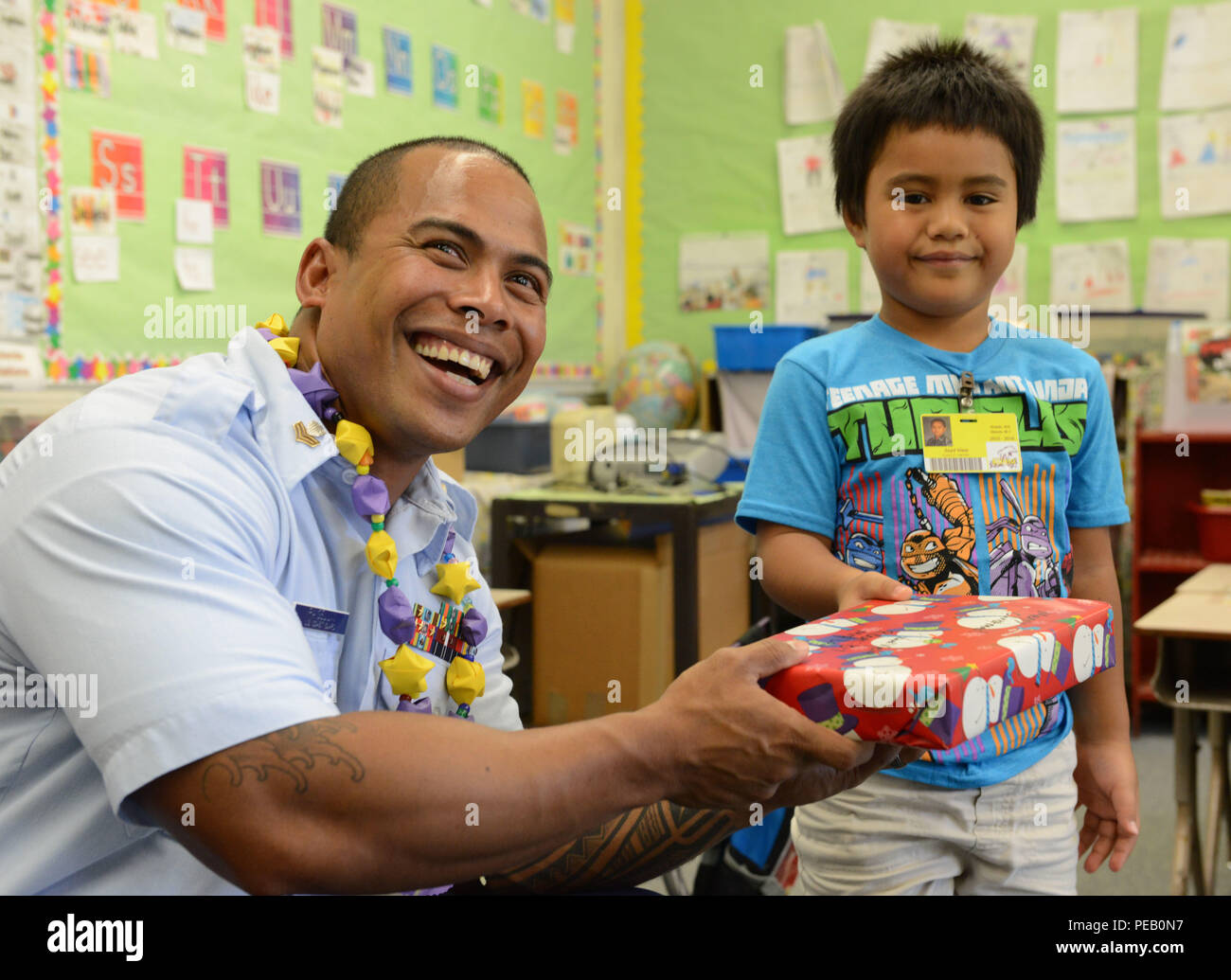 Petty Officer di prima classe Raigeluw Kensley, una di boatswain mate al Coast Guard XIV distretto, dà un regalo di Natale per un bambino in Kuhio Scuola Elementare di Honolulu, il 4 dicembre, 2015. I membri dell'equipaggio da Oahu-basato Coast Guard unità consegnate i regali di Natale per 300 bambini presso un centro cittadino di Honolulu School che preleva da un area di diseredati dell isola di Oahu. (U.S. Coast Guard foto di Sottufficiali di 2a classe di Tara Molle/rilasciato) Foto Stock