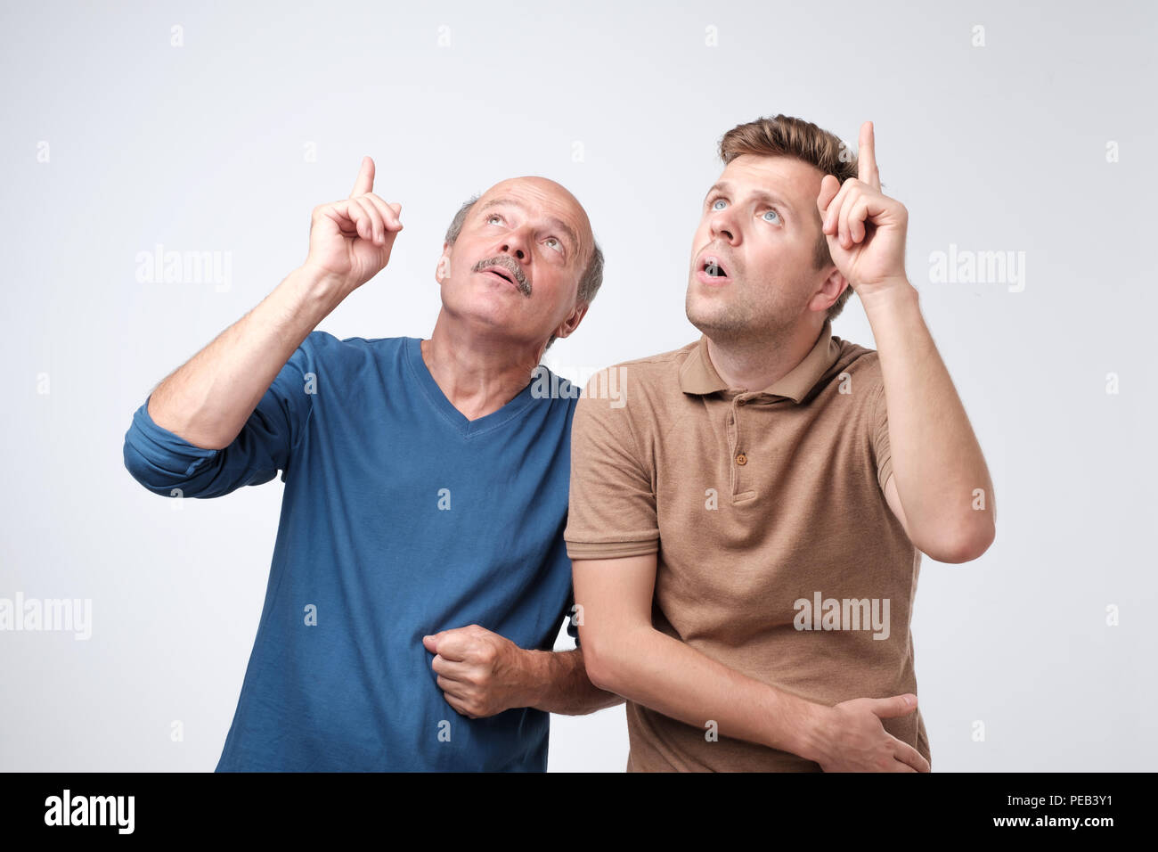 Due uomo maturo puntando con il dito indice con dubbio espressione sul viso. Qualcosa attrack la loro attenzione. Foto Stock