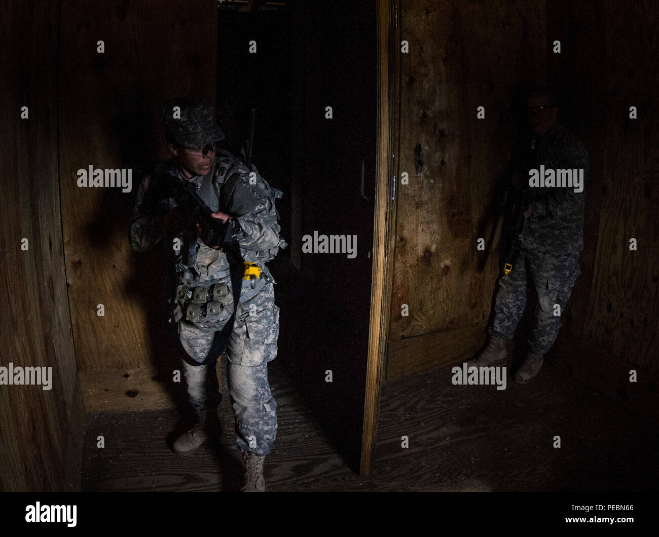 Un soldato con la forza di contrasto attende in agguato come un soldato nella base di addestramento al combattimento con la B Company, 2° Battaglione, 39o reggimento di fanteria entra in una stanza presso la Urban Assault Course si trova a Fort Jackson, S.C., Dicembre 3, 2015. (U.S. Esercito foto di Sgt. 1. Classe Brian Hamilton) Foto Stock
