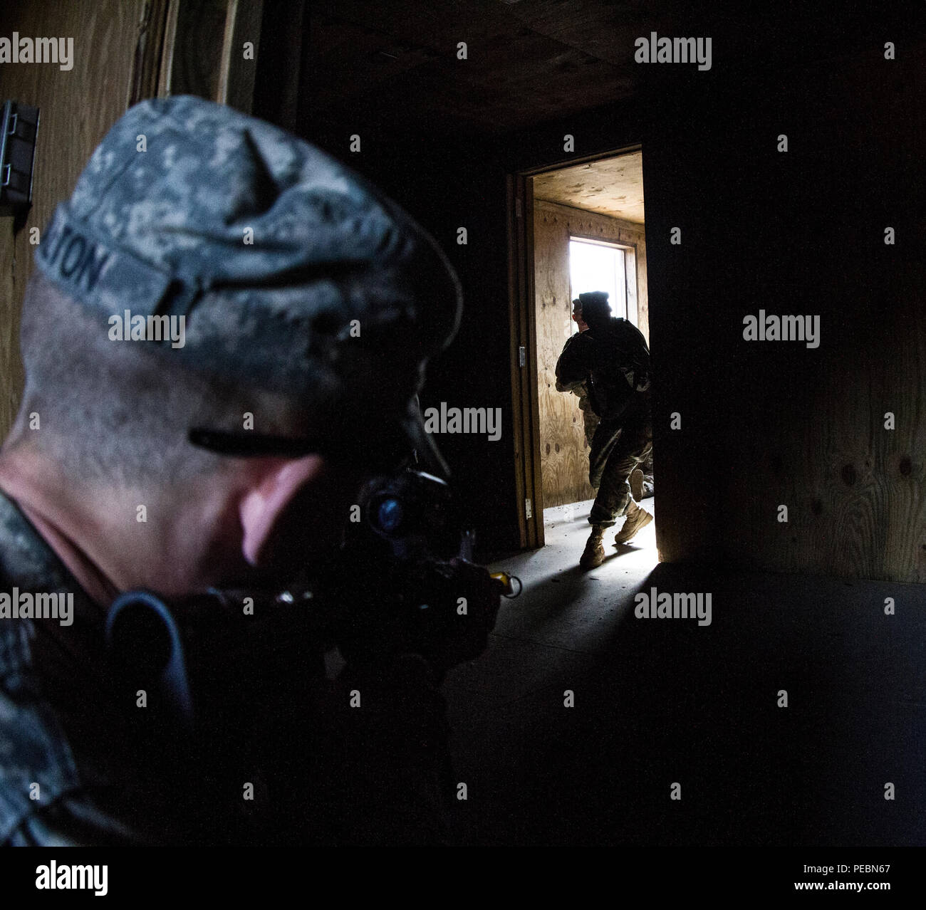Un soldato con la forza di contrasto attende in agguato come due soldati nella base di addestramento al combattimento con la B Company, 2° Battaglione, 39o reggimento di fanteria entra in una stanza a Urban Assault Course si trova a Fort Jackson, S.C., Dicembre 3, 2015. (U.S. Esercito foto di Sgt. 1. Classe Brian Hamilton) Foto Stock