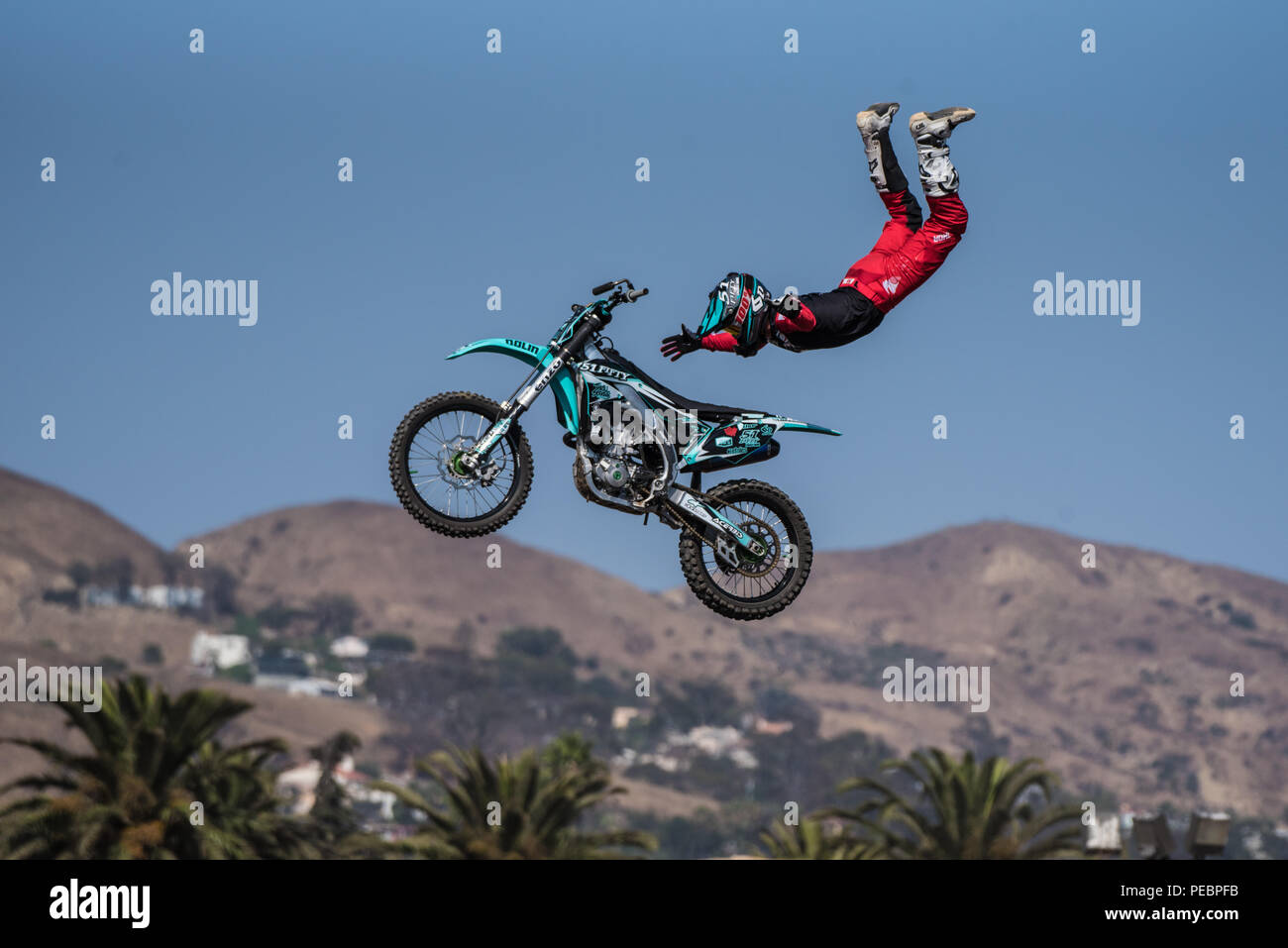 Stunt rider in costume rosso freefalls in midair su moto con le braccia distese sul salto durante battenti U Rodeo a Ventura County Fair su agosto 12, 2018 in C Foto Stock