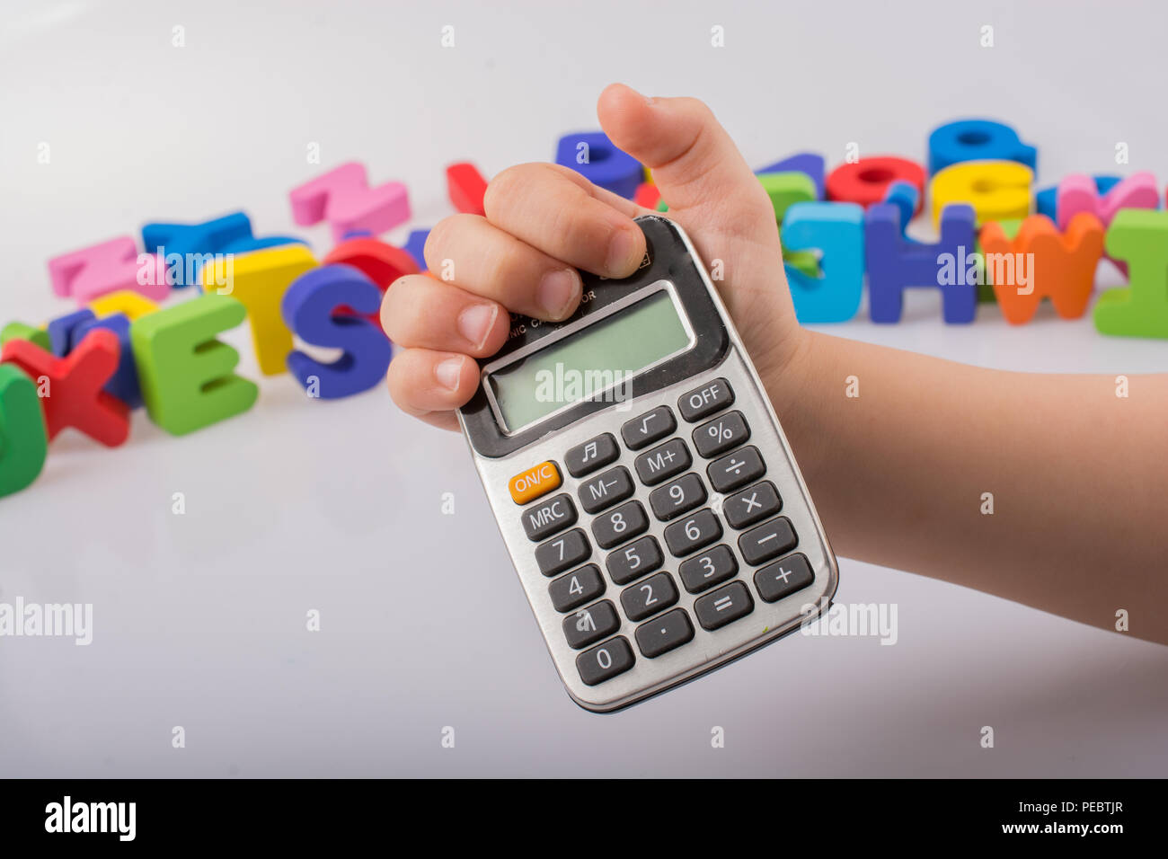 Piccola calcolatrice in mano con lettere colorate dietro su bianco Foto  stock - Alamy