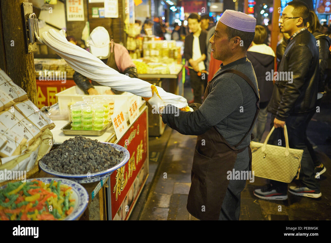 Un uomo di torsione di pasta in un mercato all'aperto, Musulmana Street, Xian, Shaanxi, Cina Foto Stock