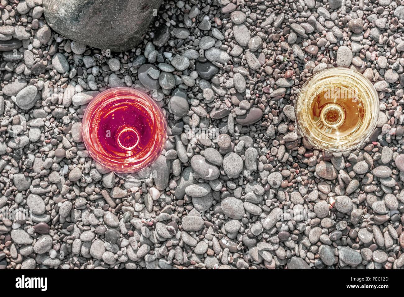 Due incantevoli bicchieri di vino bianco e rosso su ciottoli di mare Foto Stock