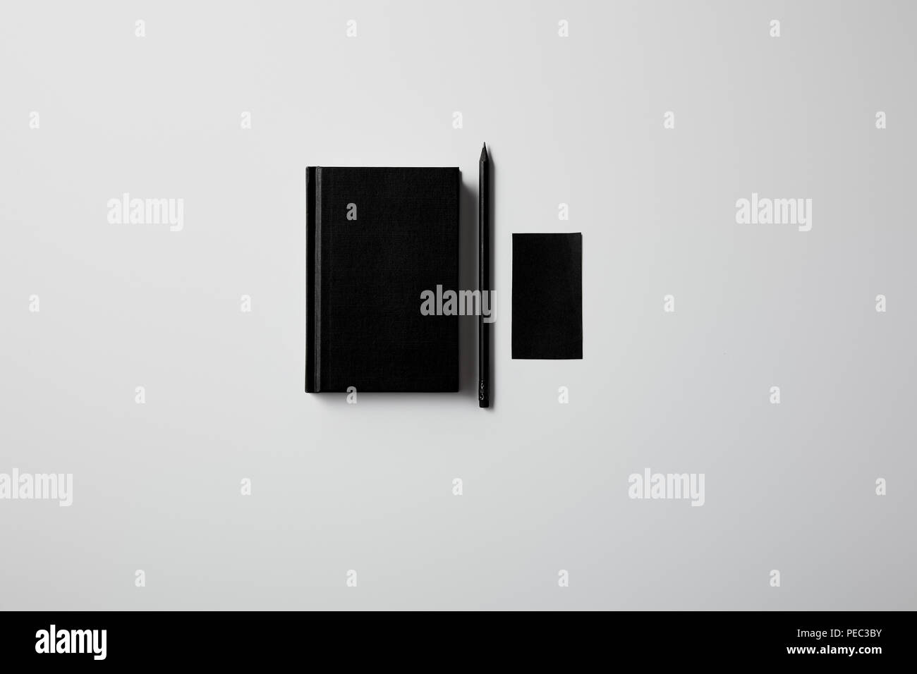 Vista superiore del notebook nero con matita e blank business card sulla superficie bianca per mockup Foto Stock