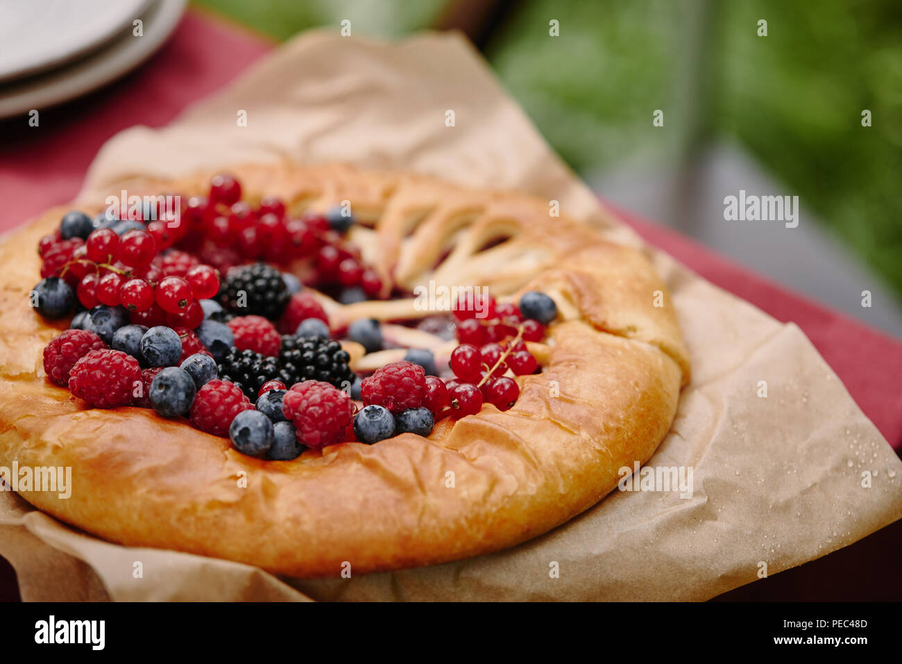 Gustosa torta con lamponi, ribes e mirtilli sul tavolo in giardino Foto Stock Gustosa torta con lamponi, ribes e mirtilli sul tavolo in giardino Foto Stock