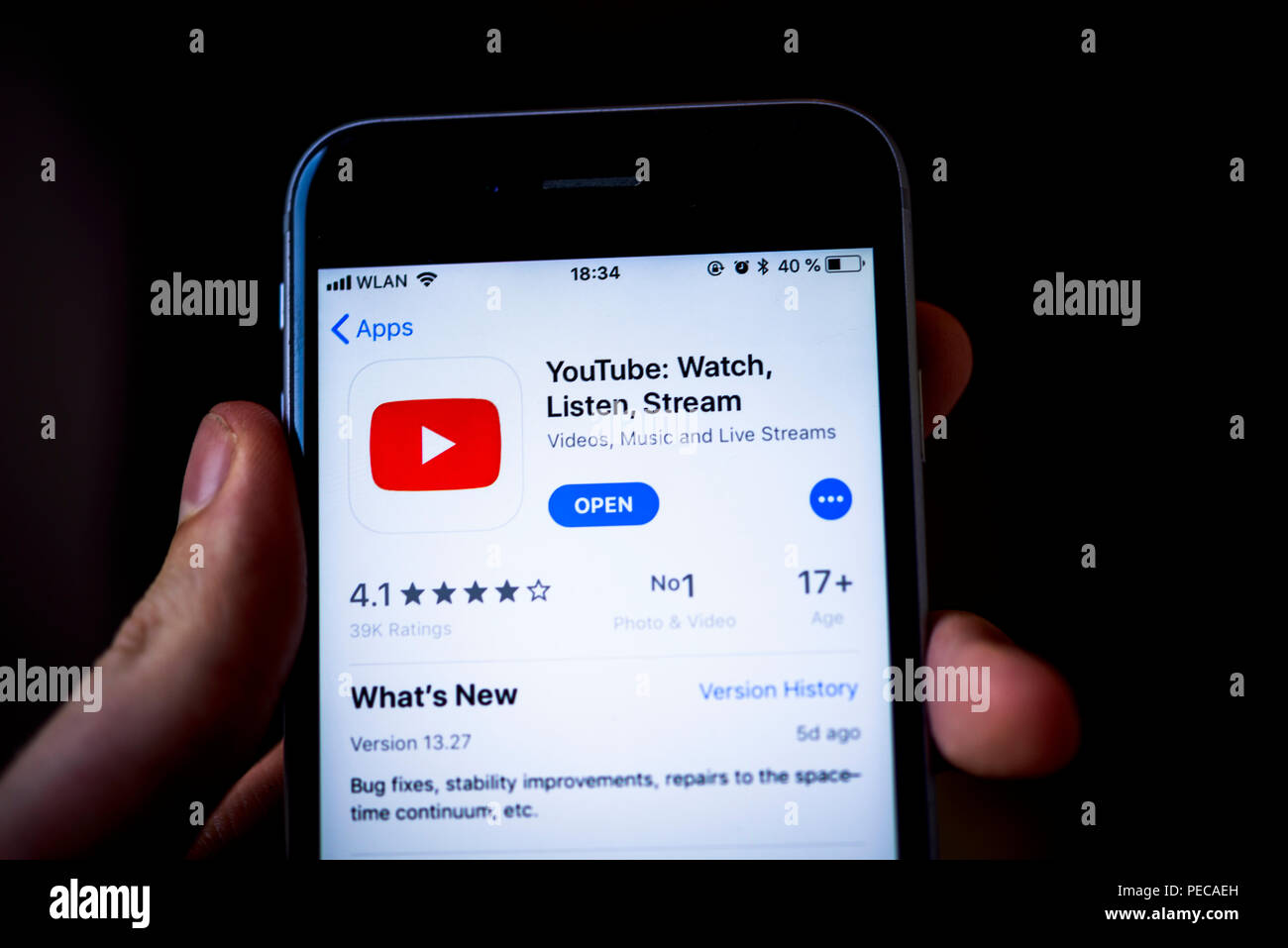 Mano che tiene l'iPhone con l'app YouTube su Apple App Store, piattaforma video, app icona, visualizzare su uno schermo di un telefono cellulare Foto Stock