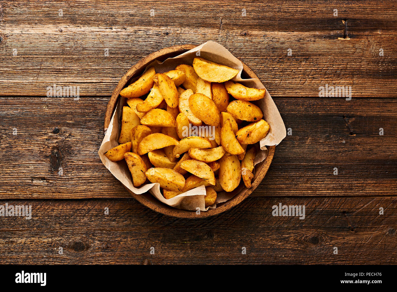 Patate arrosto in ciotola sul tavolo di legno con copia spazio. Foto Stock