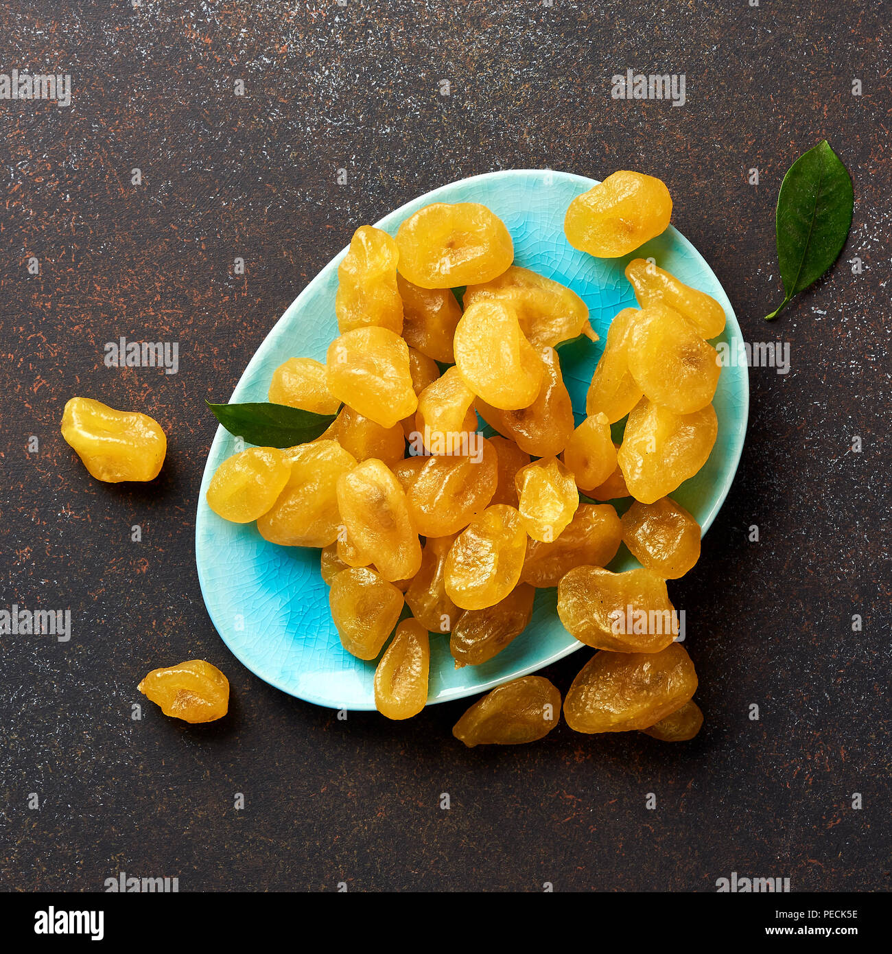 Giallo essiccato kumquat con foglie verdi su sfondo marrone. Vista dall'alto. Foto Stock