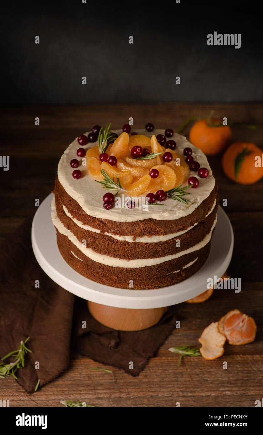 La torta al cioccolato con clementine, mirtillo e rosmarino cakestand sfondo di legno. Ancora in vita. Foto Stock