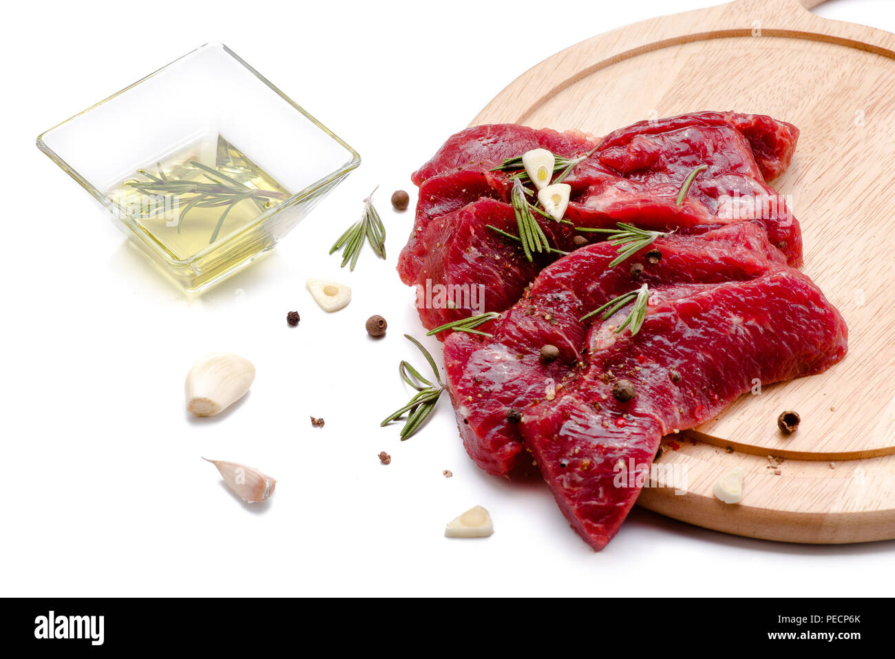 Pezzi di carne con aglio e rosmarino isolati su sfondo bianco. Carne di manzo crudo. Foto Stock