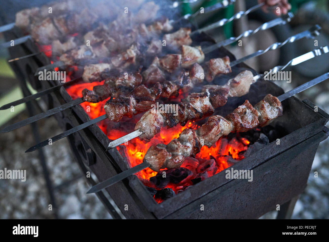 Spiedini preparazione su un grill barbecue a carbone. Pezzi di carne su spiedini. Shish kebab preparare sul fuoco. Foto Stock