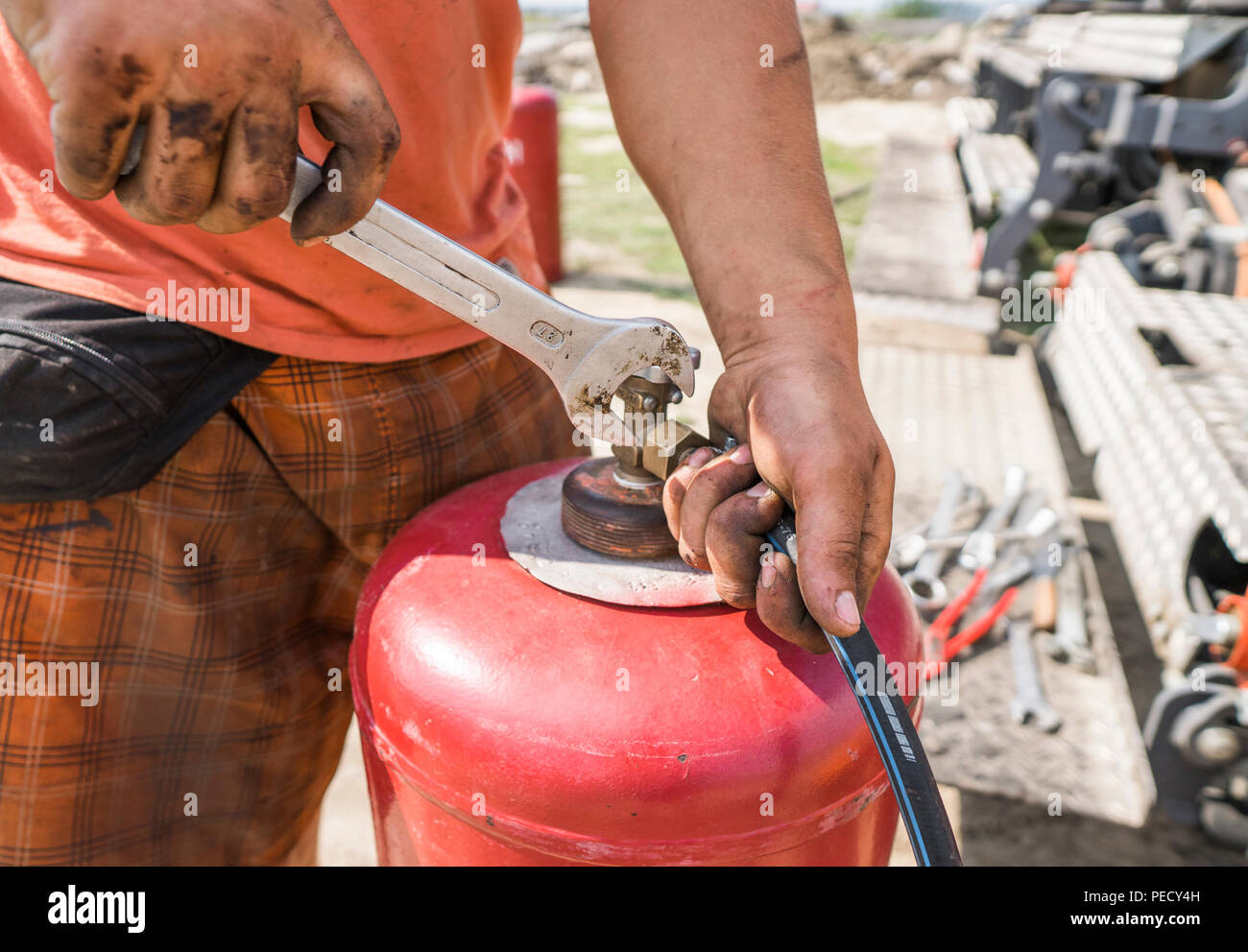 L'uomo avvitare il tubo alla bombola del gas con una chiave Foto Stock