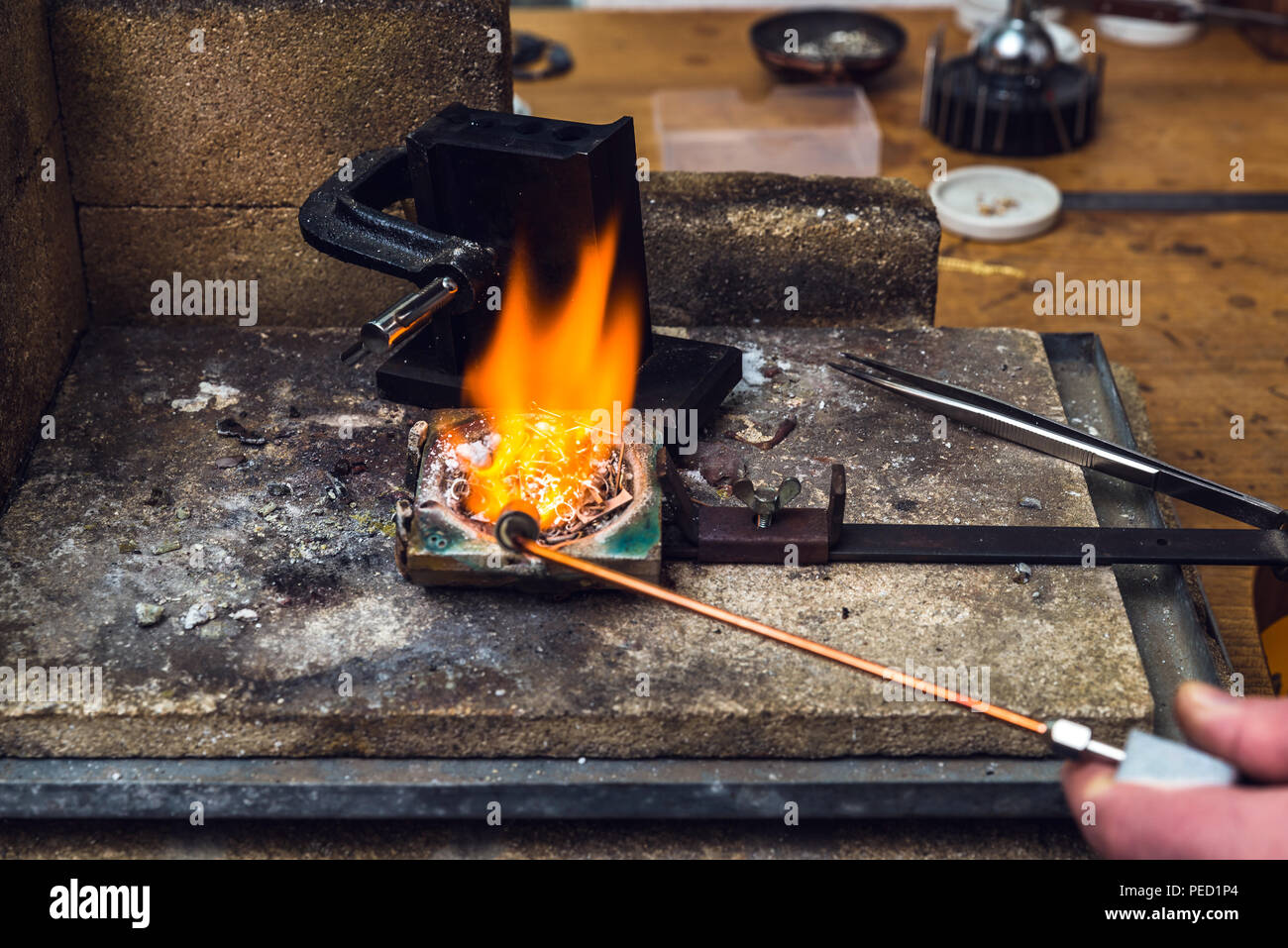 Basso punto di fusione del metallo in ottone con una fiamma di torcia in un  crogiolo al posto di lavoro di orafo per eseguire l'artigianato lamiera  Foto stock - Alamy