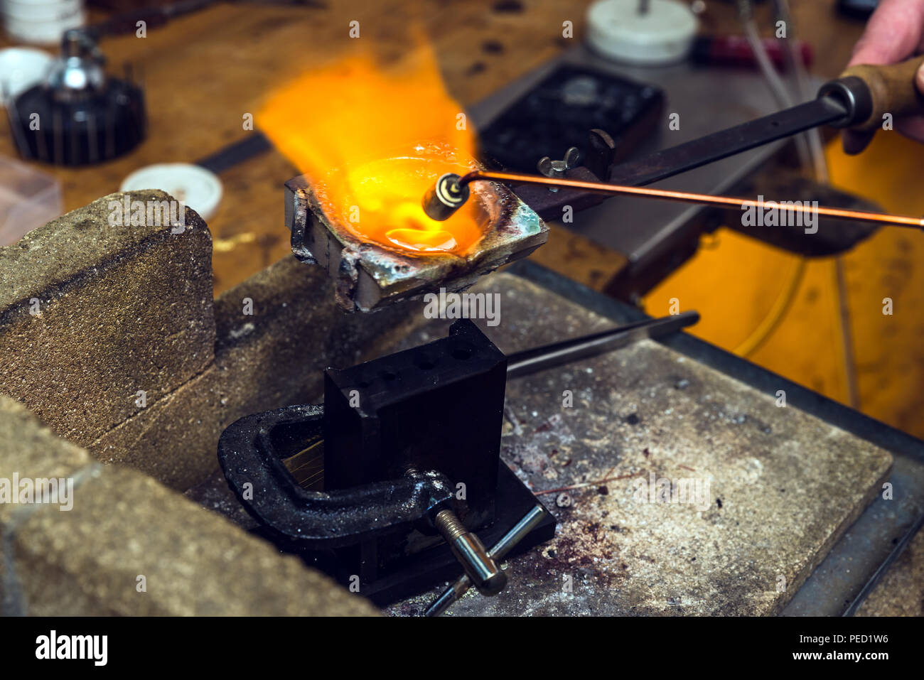 Basso punto di fusione del metallo in ottone con una fiamma di torcia in un  crogiolo al posto di lavoro di orafo per eseguire l'artigianato lamiera  Foto stock - Alamy