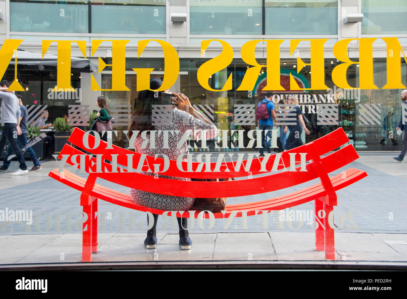 Una donna seduta su uno di Jeppe Hein modificati di banchi sociale a Londra il South Bank, SE1, Regno Unito Foto Stock