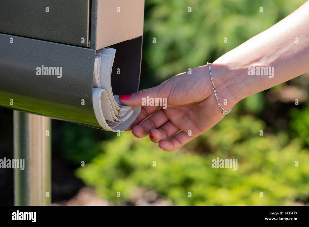 Una donna prende il giornale fuori da una cassetta postale. Foto Stock