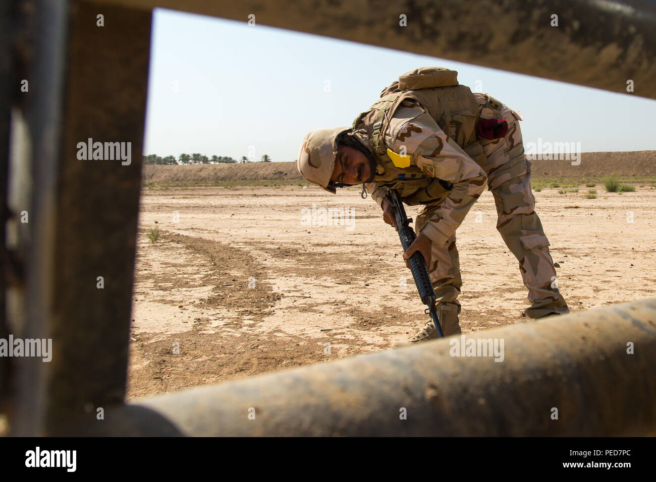 Un soldato iracheno assegnato al ventitreesimo esercito iracheno brigata guarda sotto un Humvee durante l'esecuzione di cinque e 25 metri di controlli durante il contatore esplosivi improvvisati per la formazione del dispositivo a Camp Taji, Iraq, 2 agosto 2015. Formazione presso l'edificio la capacità del partner sites è parte integrante della Combined Joint Task Force - Funzionamento inerenti risolvere la multinazionale di sforzo per treno iracheno forza di sicurezza personale per sconfiggere lo Stato islamico dell Iraq e il levante. Una coalizione di nazioni si sono unite insieme per sconfiggere ISIL e la minaccia che essi rappresentano per l'Iraq, Siria, della regione e della più ampia comunità internazionale. (Brevetto statunitense n. Foto Stock