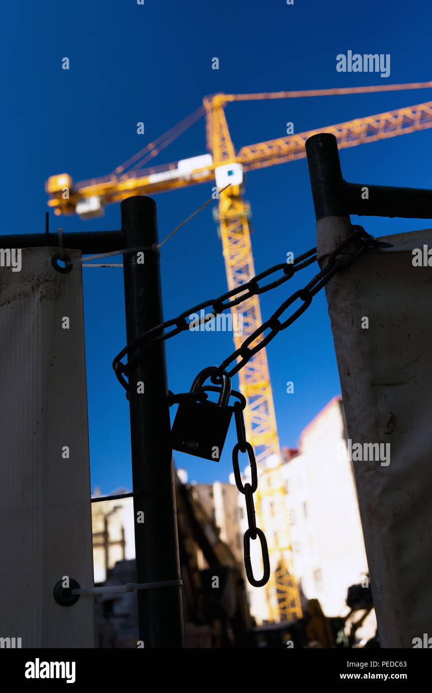 La Lettonia Riga. Bloccare e la catena sul gate edificio su uno sfondo di colore giallo gru e un luminoso cielo blu Foto Stock