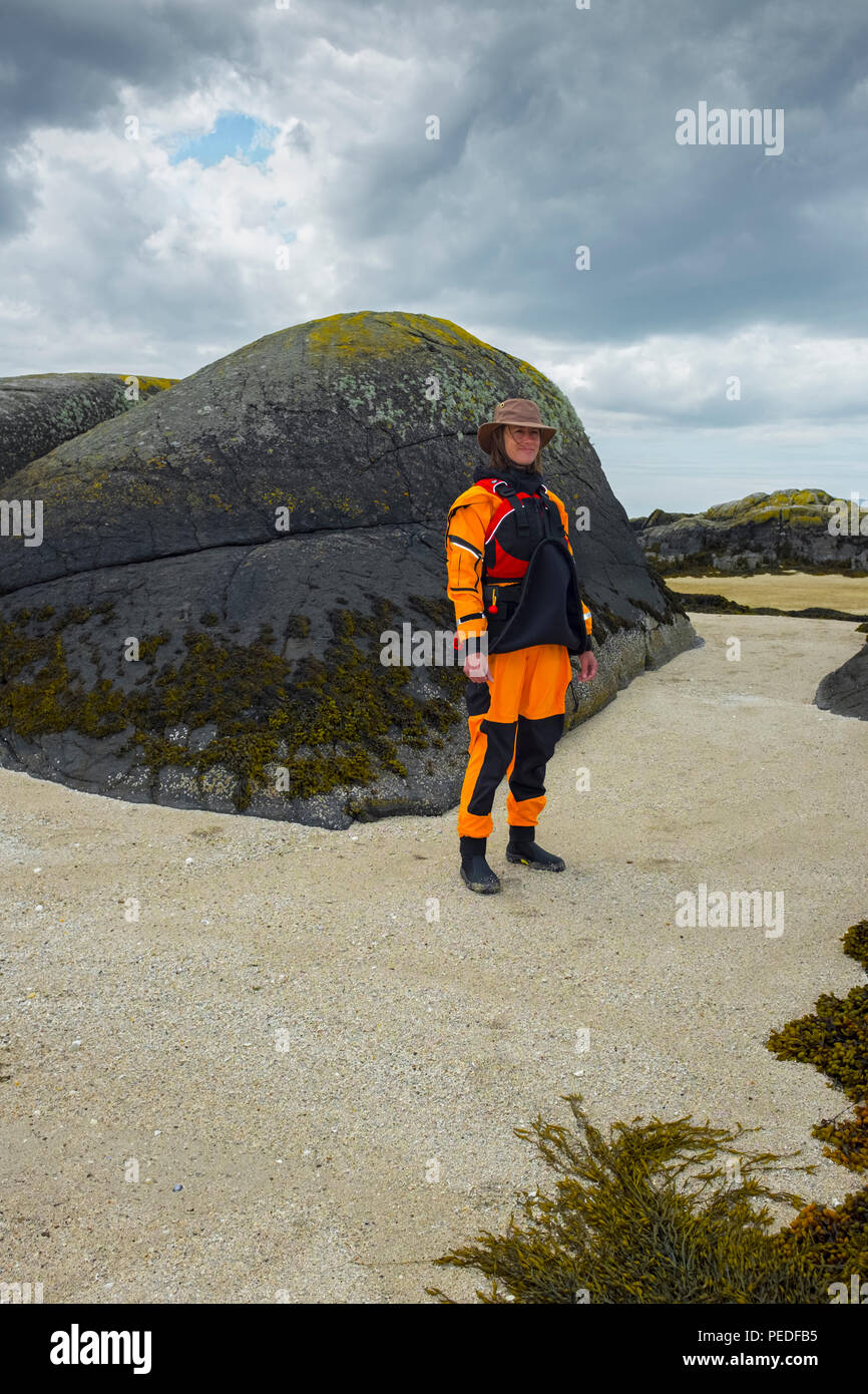 Giovane donna kayaker di mare indossando un giallo brillante drysuit. Foto Stock