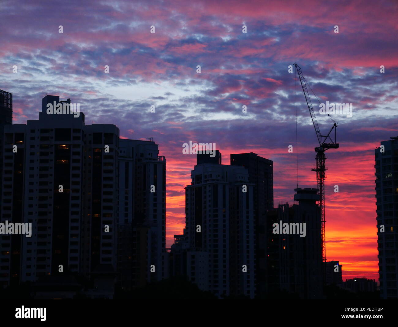 Tramonto dietro gli edifici con un bellissimo cielo nuvoloso. Bel rosso, viola e le sfumature di blu del tramonto dietro gli edifici moderni Foto Stock