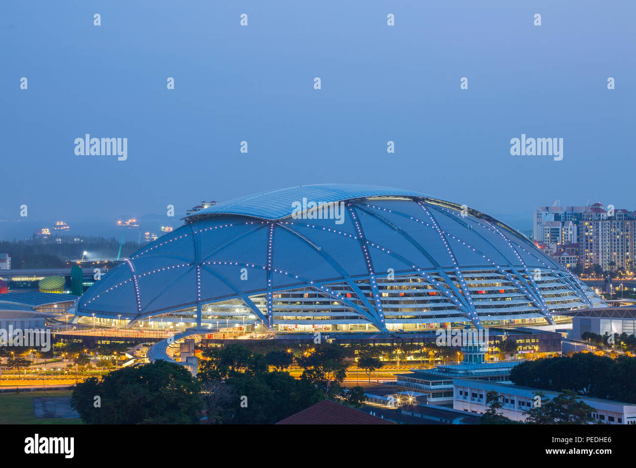 Architettura del polo sportivo di Singapore durante l'ora magica in serata. L'enorme tetto è parzialmente illuminato. Foto Stock