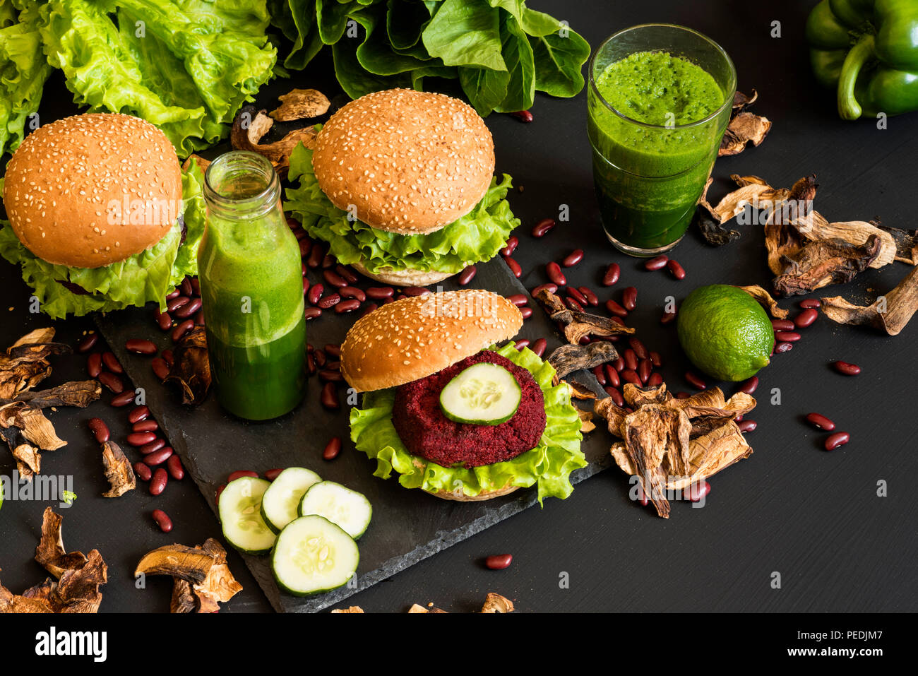 Hamburger vegano con fettine di barbabietole e frullati verdi su sfondo nero. Sano cibo vegan. Detox dieta. Foto Stock