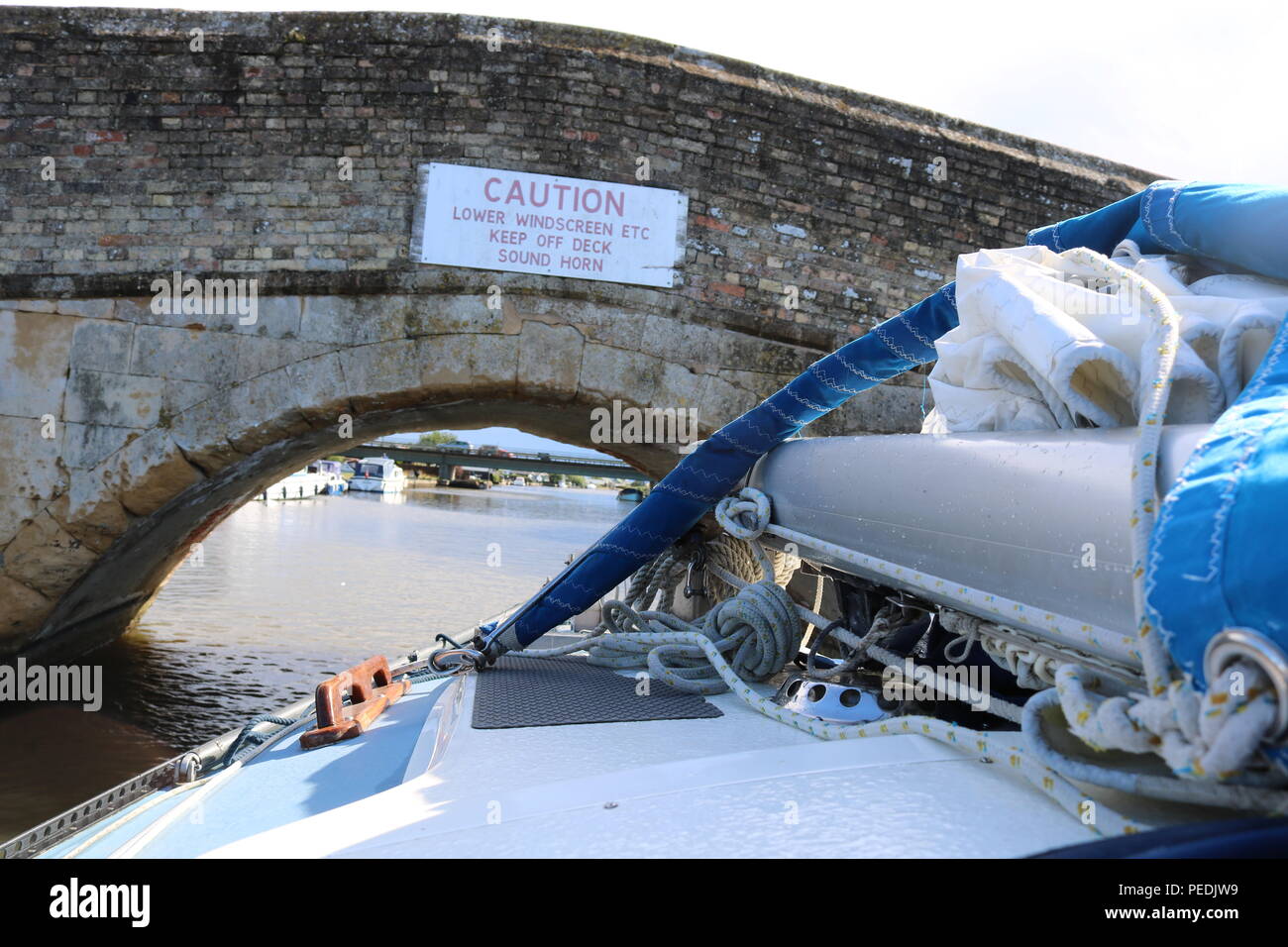 Barca con montante abbassato come si passa sotto il ponte romano di Potter Heigham su Norfolk Broads Foto Stock