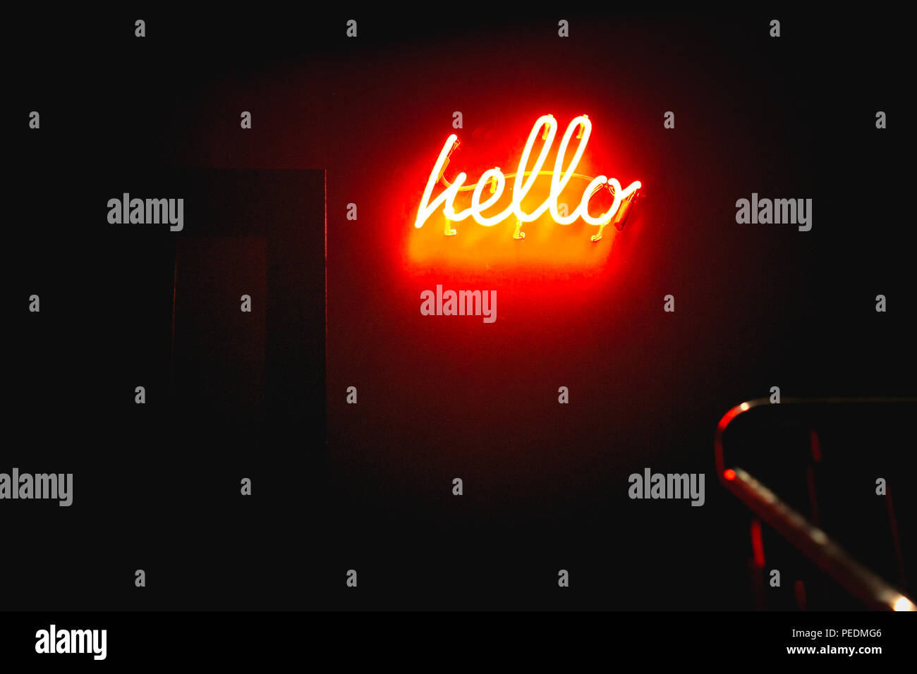 Una scritta al neon che dice ciao su una parete rossa in un corridoio scuro di notte Foto Stock