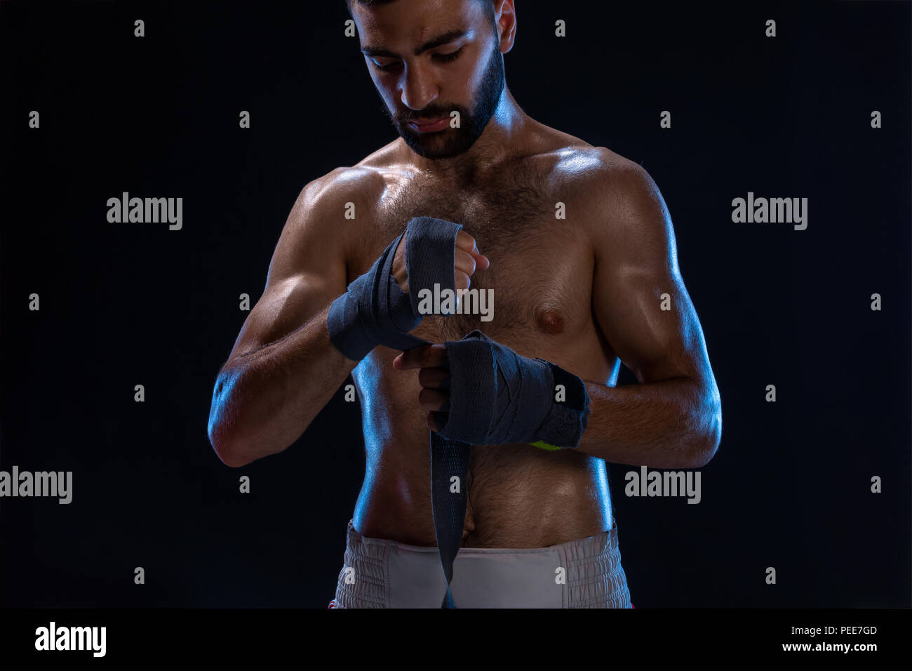 Sport boxer uomo tira su la mano avvolge il polso. Oriental modello maschile isolato su sfondo nero. Foto Stock