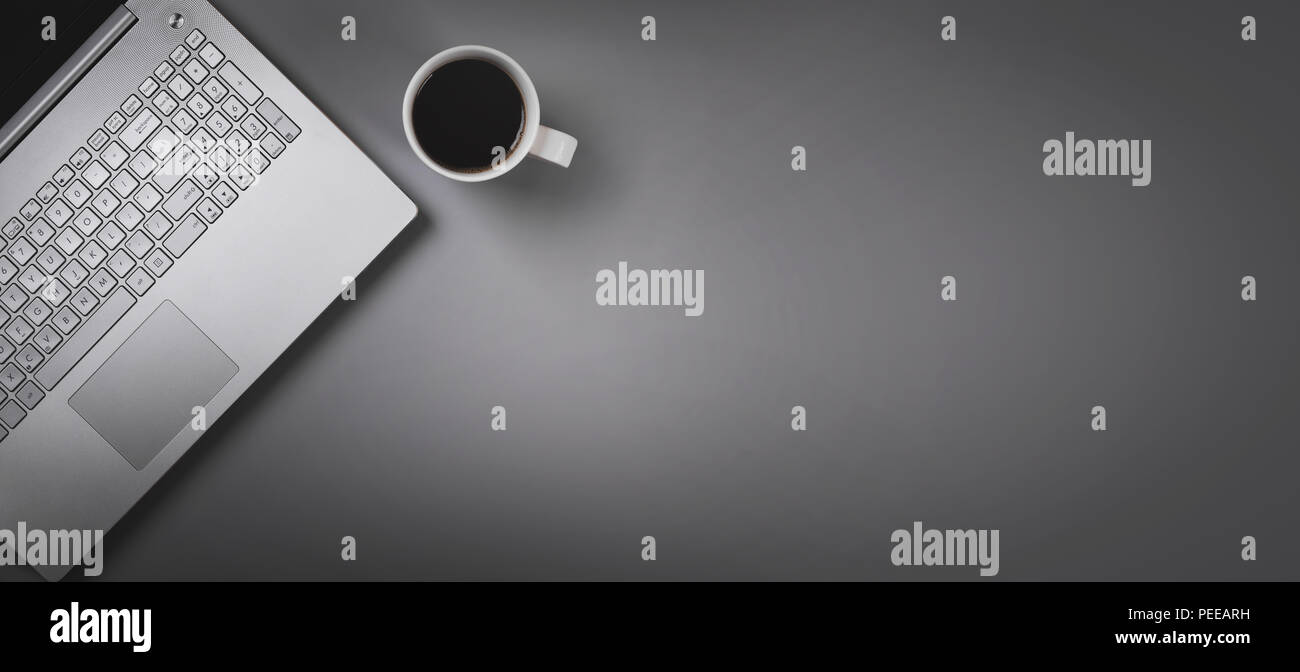 Laptop e la tazza di caffè su sfondo grigio con copia spazio. vista superiore Foto Stock