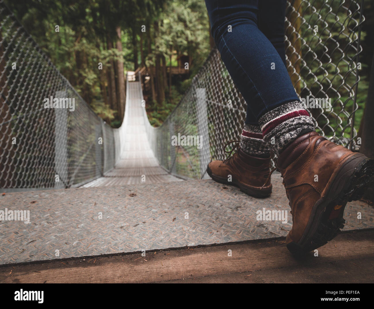 Scarpe da trekking nella parte superiore di un ponte di sospensione in una foresta. Foto Stock