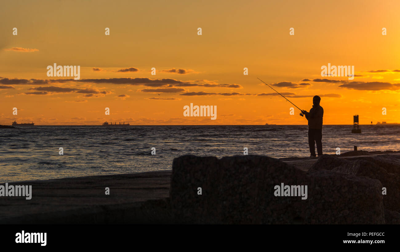 Un uomo pesca su un molo su una spiaggia del Texas di sunrise Foto Stock