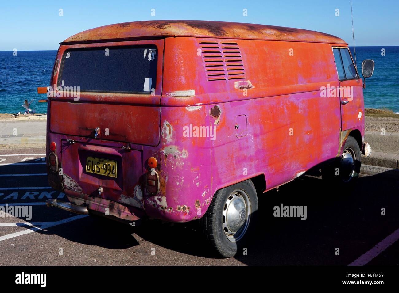 Close Up di travagliato, arancione e rosa VW camper a soldati spiaggia, Nuovo Galles del Sud, Australia Foto Stock