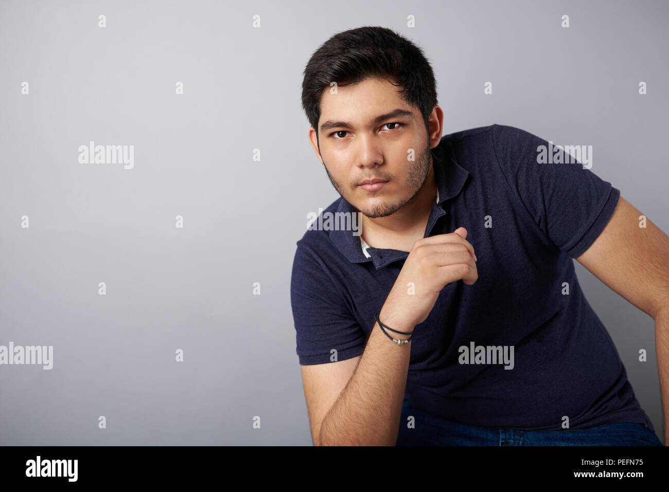 Bel giovane uomo ritratto in grigio di sfondo per studio Foto Stock