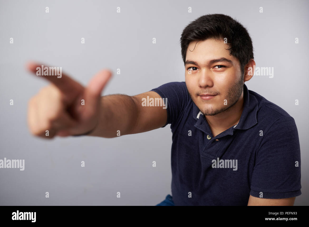 Giovane uomo punto dito nella telecamera isolata su studio uno sfondo grigio Foto Stock