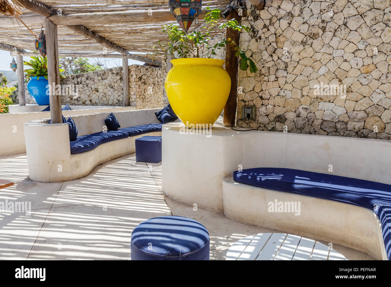 Lo stile mediterraneo interno in giallo, bianco e blu con rustici ramoscello soffitto a strisce che forniscono ombra su divani e cuscini, pavimenti in legno Foto Stock