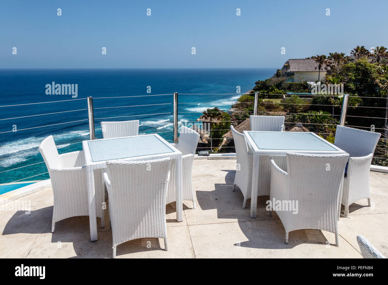 Tavoli e sedie bianchi a una scogliera outdoor cafe con vista oceano, Ungasan, Bali, Indonesia. Foto Stock