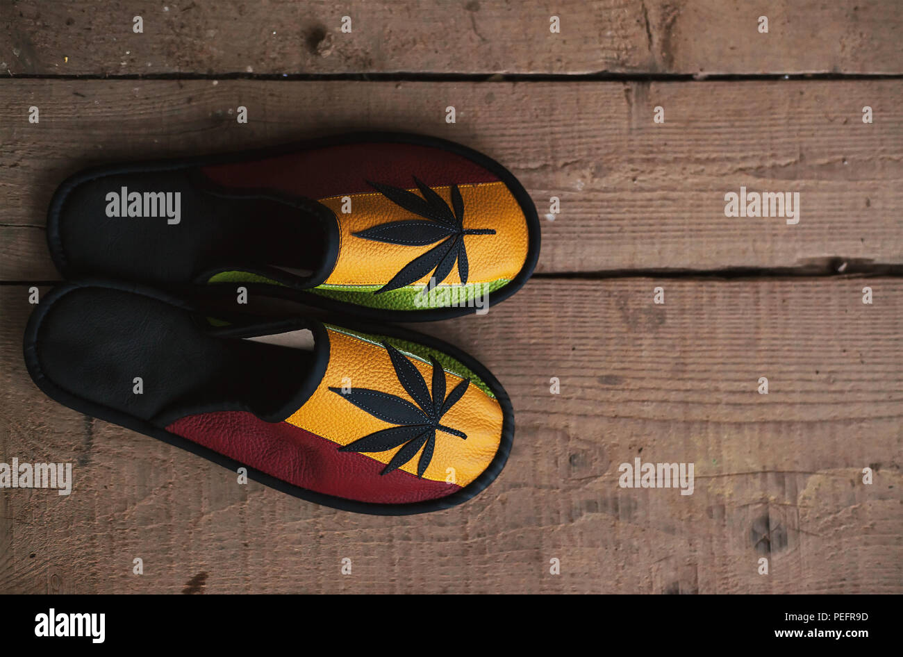 Nuovo di zecca scarpe colorate con la marijuana simbolo sulla parte superiore, sul vecchio pavimento in legno. Foto Stock