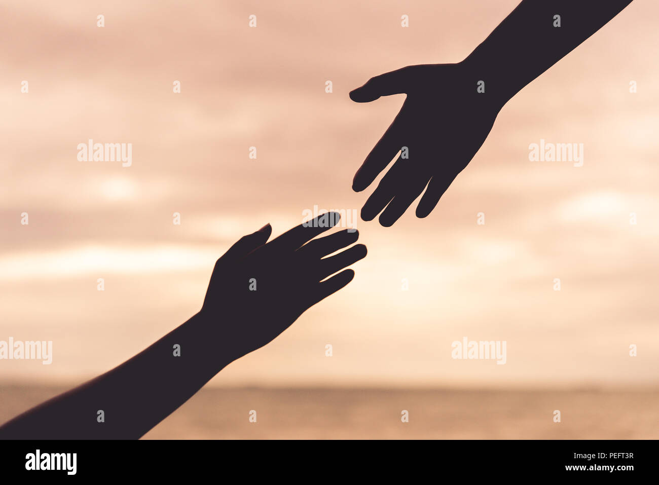 Silhouette aiutando le mani su sfocato il mare e il cielo dello sfondo. Amicizia giorno concetto. Foto Stock