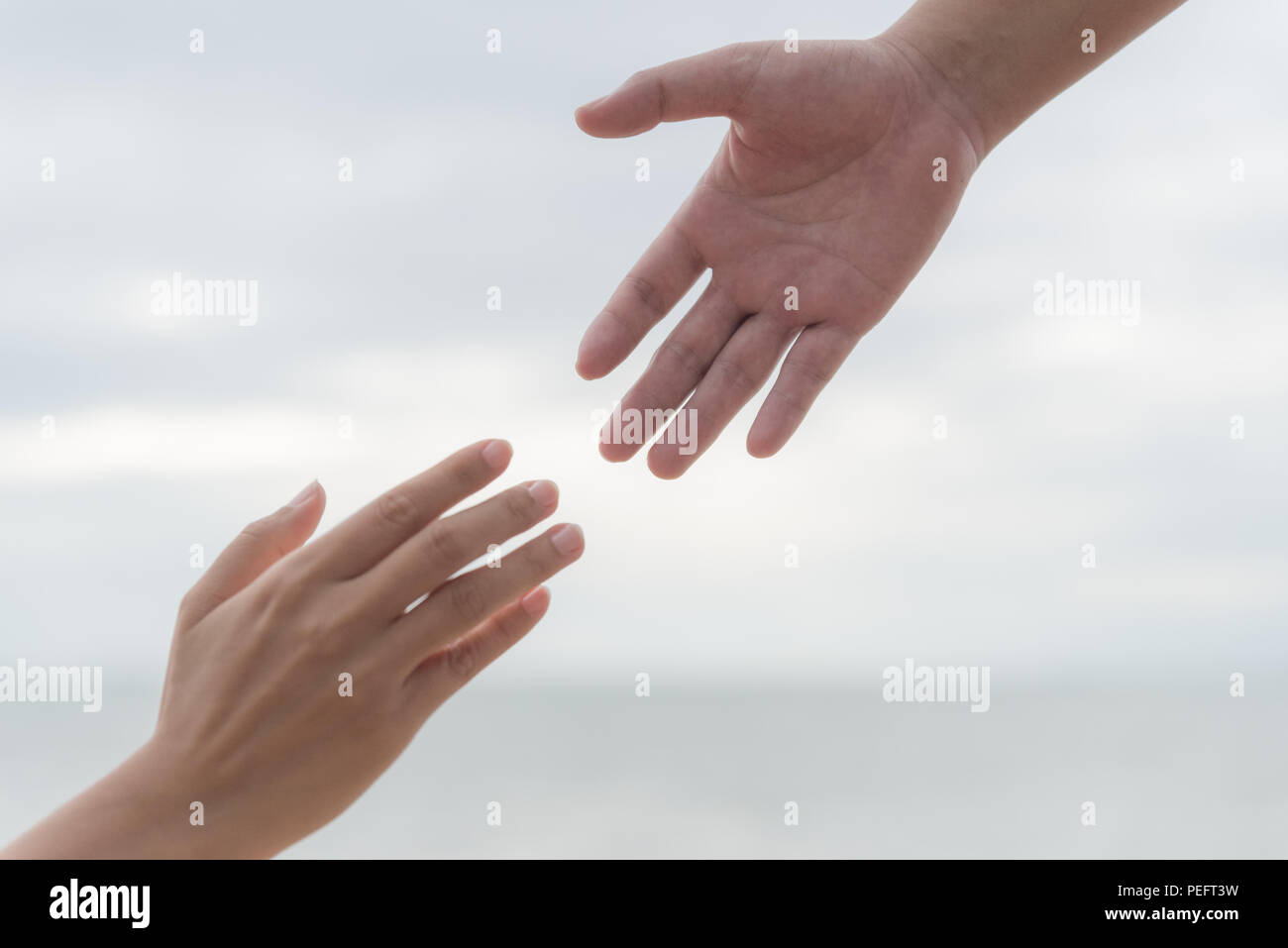 Aiutando le mani su sfocato il mare e il cielo dello sfondo. Amicizia giorno concetto. Foto Stock