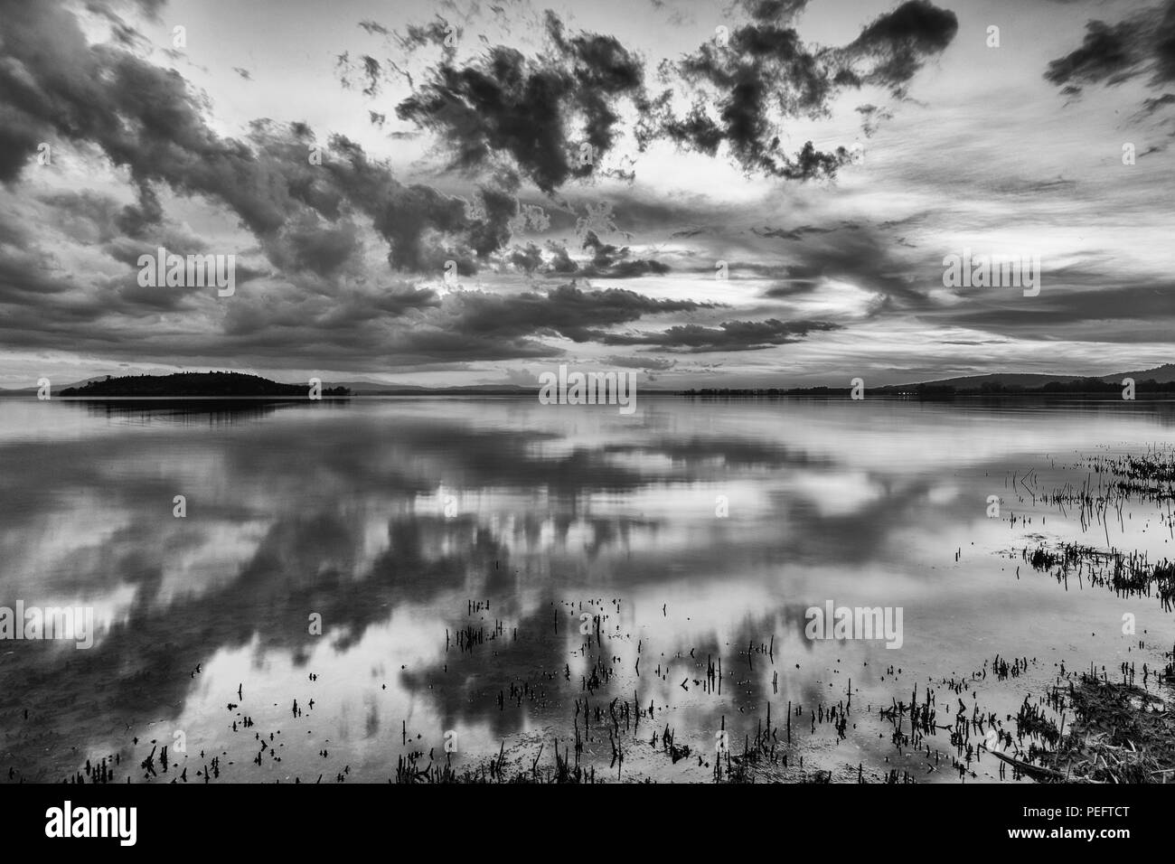 Perfetta e simmetrica nuvole e isole riflessioni su un lago, rendendo le forme astratte Foto Stock