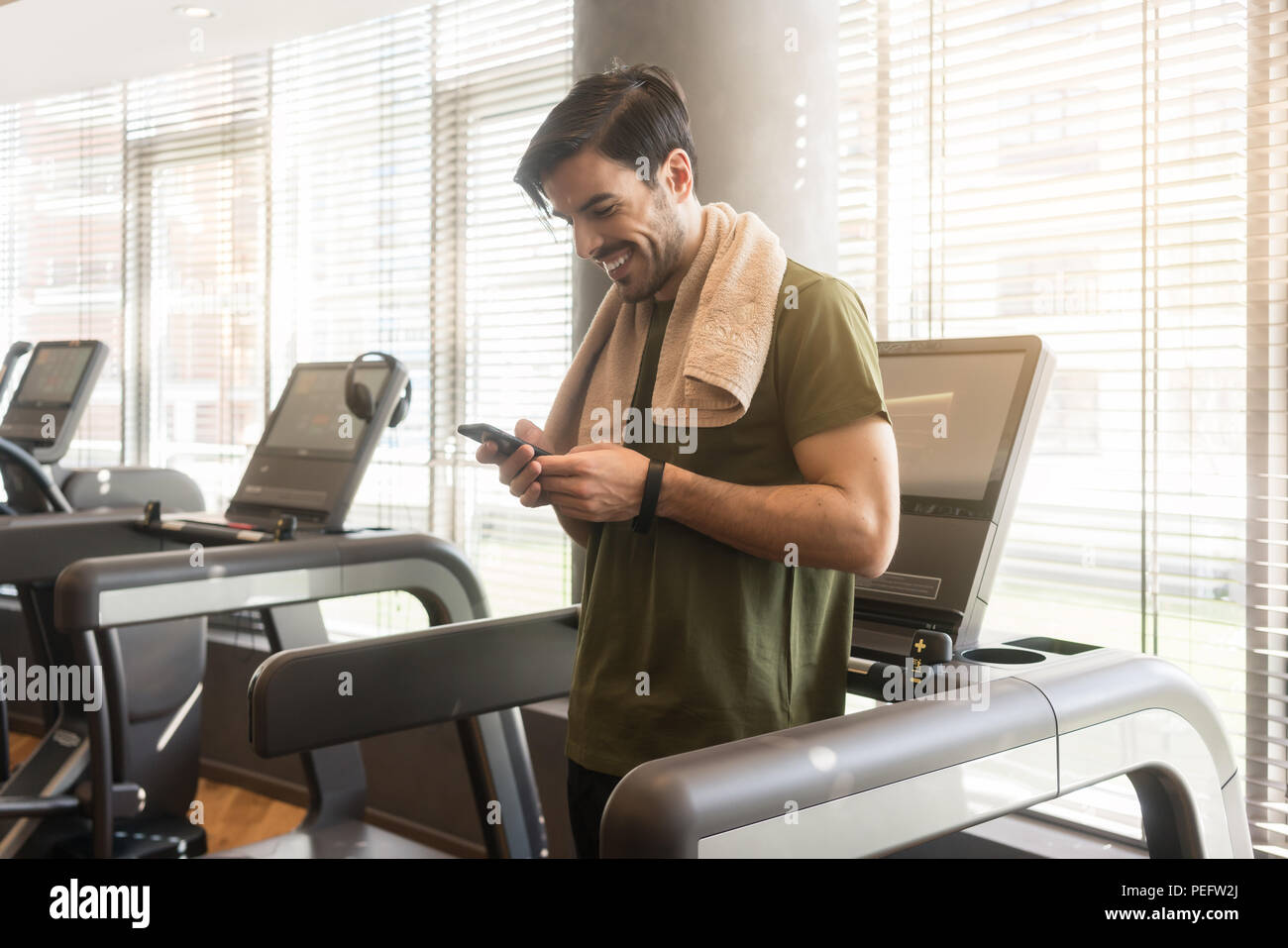 Giovane uomo sorridente durante la comunicazione del telefono cellulare durante la pausa Foto Stock