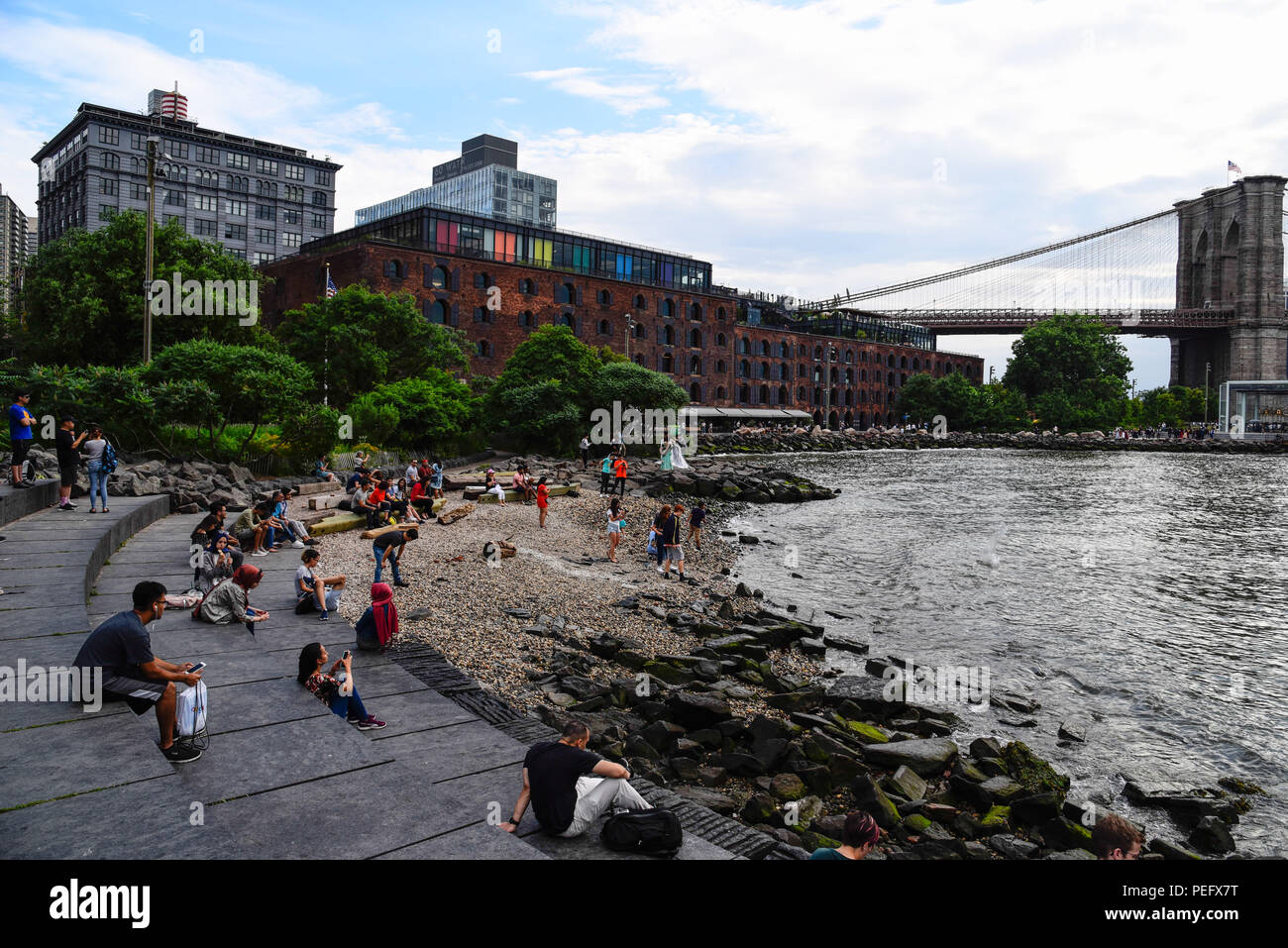 La città di New York, Stati Uniti d'America - 20 Giugno 2018: persone di godere in passeggiata da East River in DUMBO, Brooklyn, guardando skyline di Manhattan al tramonto Foto Stock