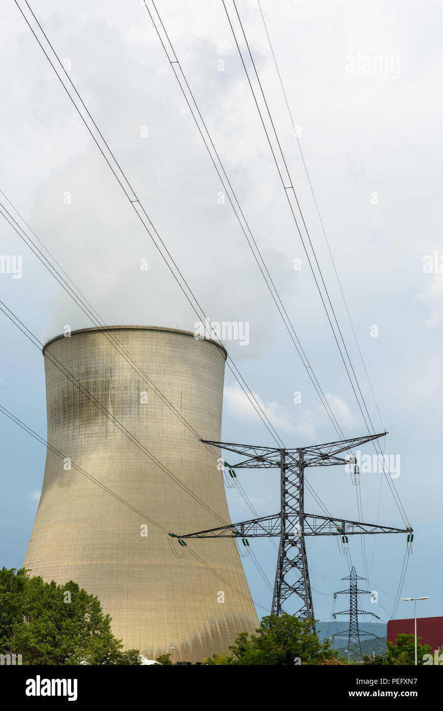 Una torre di raffreddamento di un impianto ad energia nucleare rilasciando le nubi di vapore di acqua con una torre di trasmissione di sostenere una tensione elevata linea elettrica aerea in th Foto Stock