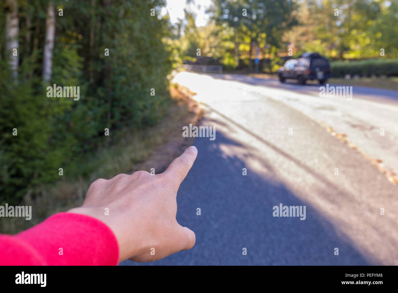 Persona della mano e dito indice puntato dritto su una strada, dare indicazioni Foto Stock